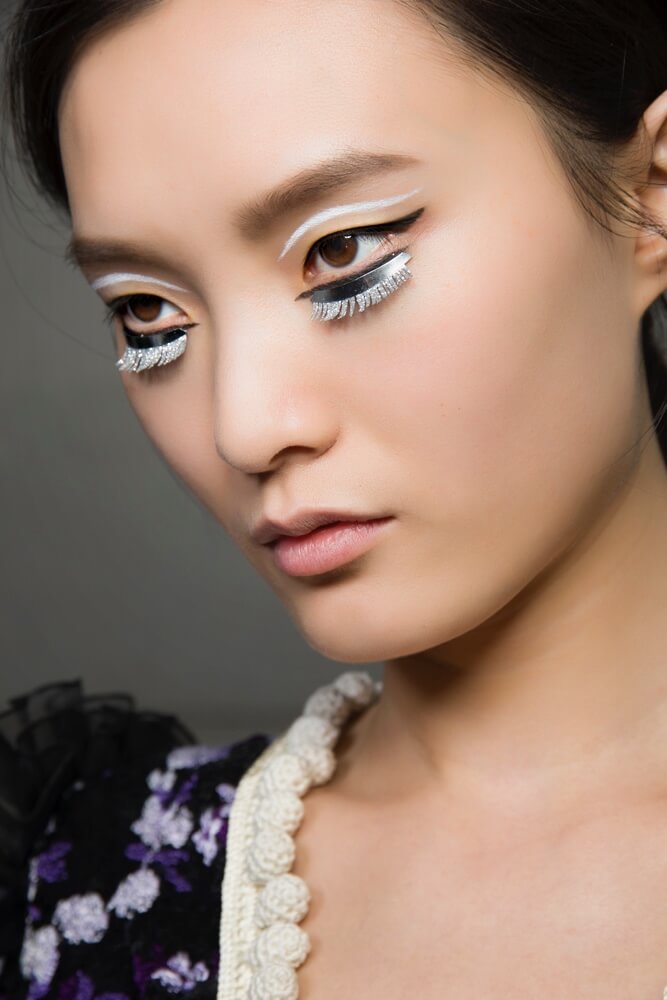 Close-up of a woman's face with creative white and black makeup for a beauty campaign.