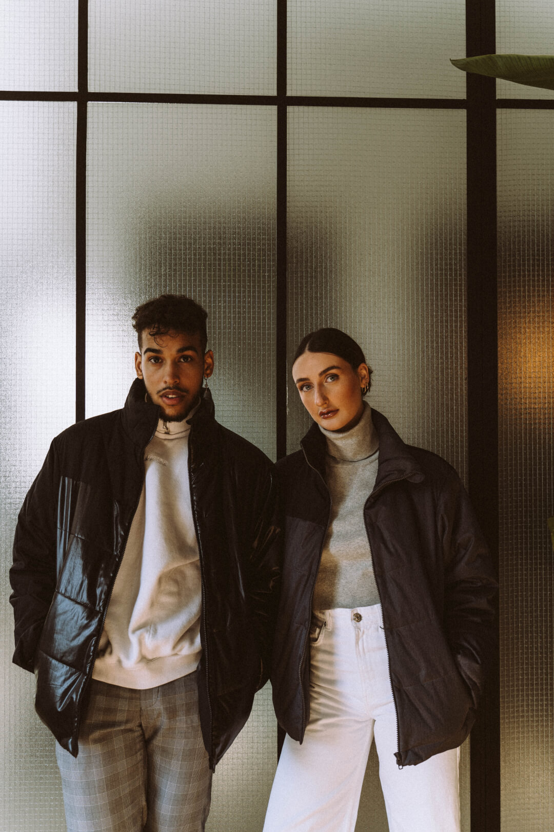 A stylish couple poses indoors, showcasing modern winter fashion and casual urban lifestyle apparel.