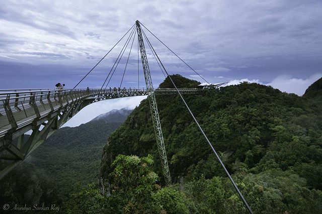 Scenic view of the Langkawi Sky Bridge in Malaysia, offering a tranquil experience among lush mountains and cloudy skies.