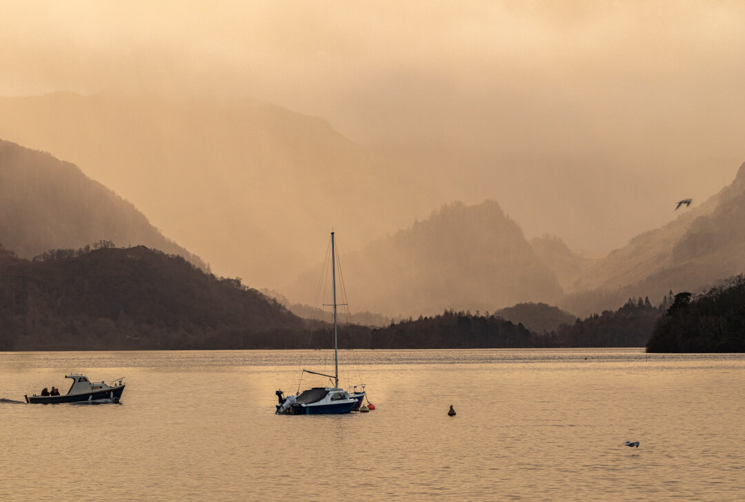 A scenic view of boats on a tranquil lake with mountains in the background.