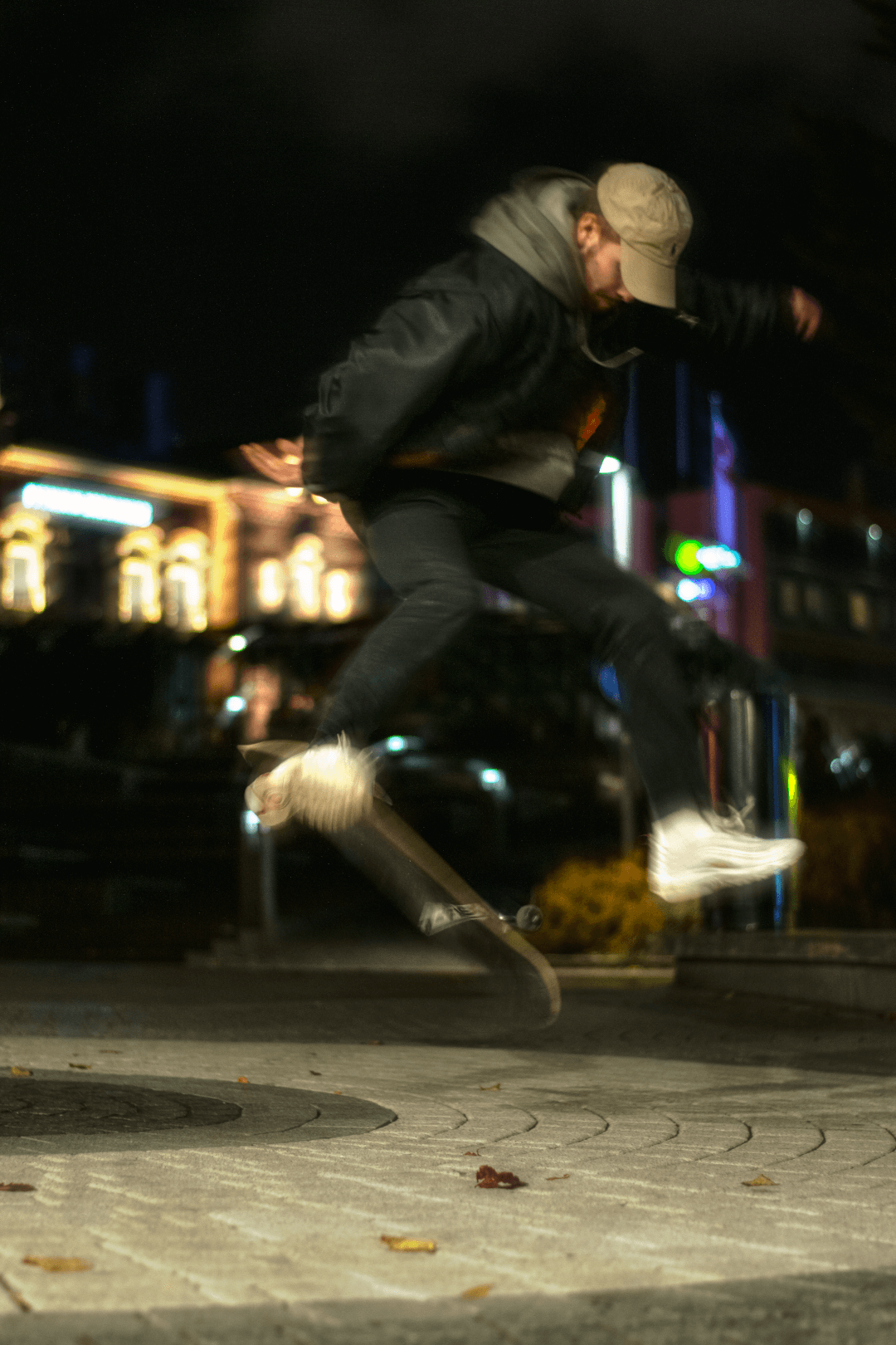 A skateboarder performs a trick at night in an urban setting with motion blur.