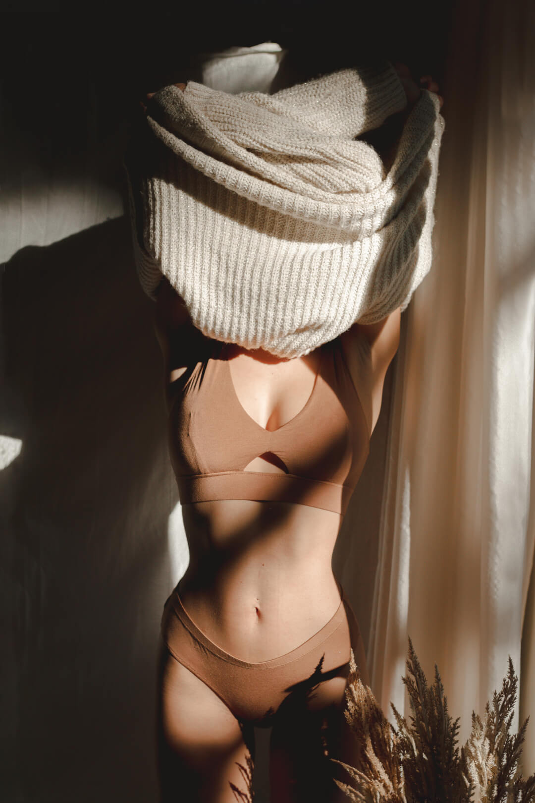 A woman undressing in soft light, promoting body positivity and self-care.