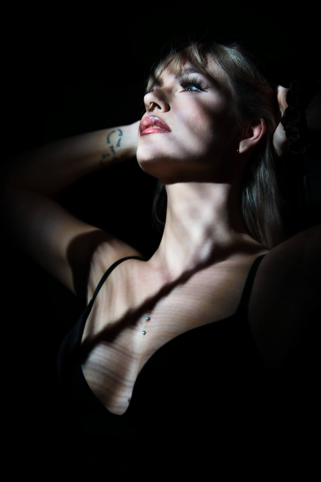 A woman poses intimately in the shadows, creating a sensual and artistic portrait. 