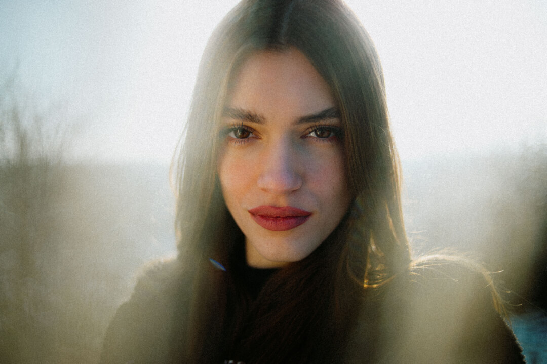 Portrait of a serene woman in nature with soft, natural lighting for beauty and wellness campaigns.