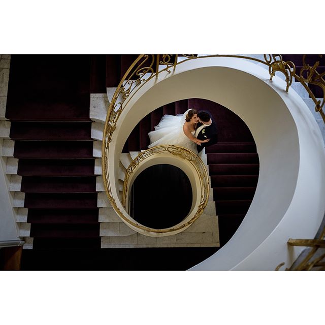 A bride and groom embrace on a spiral staircase, symbolizing their love and commitment on their wedding day.