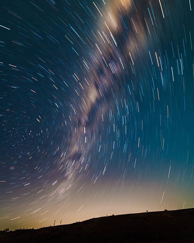 A stunning long exposure shot captures star trails over a silhouetted landscape, blending science and nature.