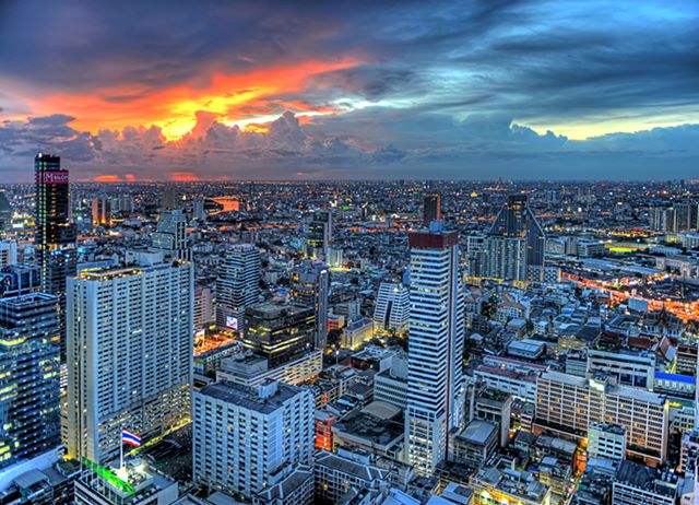 A vibrant cityscape at sunset, with skyscrapers glowing against an orange and blue sky.