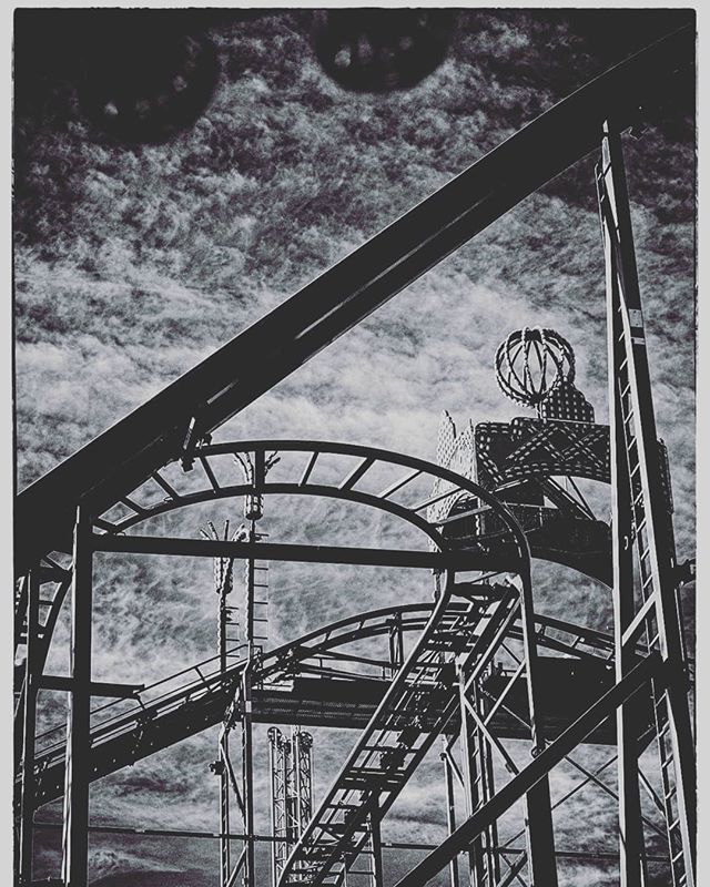 A black and white image of a thrilling roller coaster in an amusement park, evoking a sense of excitement and nostalgia.