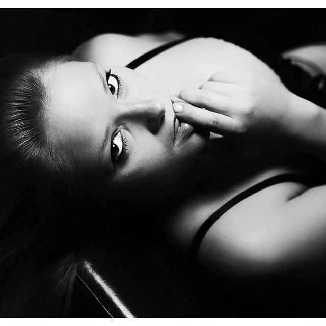 A sensual black and white portrait of a woman with soft lighting in a studio.