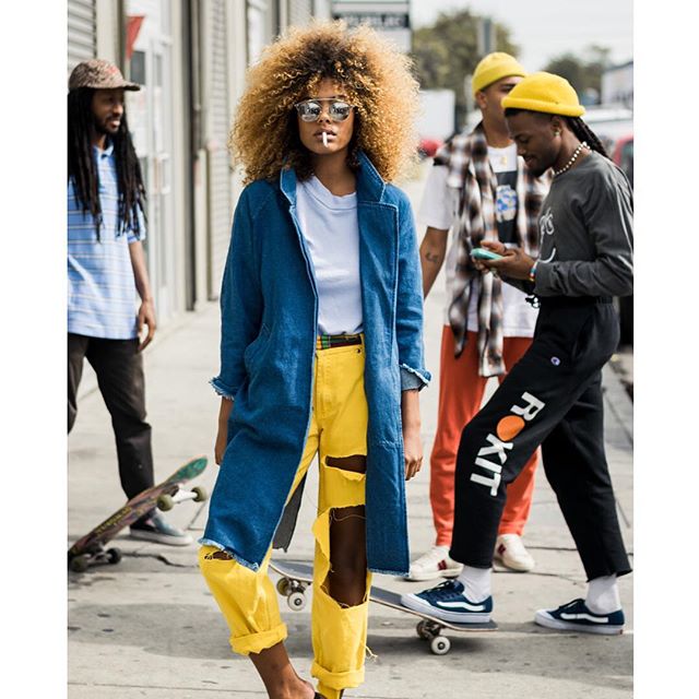 A stylish woman poses with friends on the street, showcasing urban fashion and lifestyle.