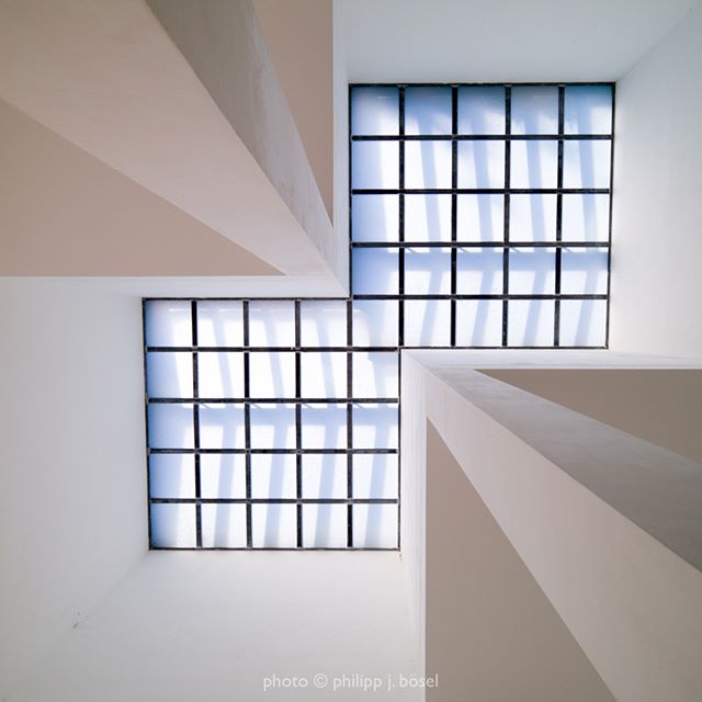 Architectural detail featuring two square windows in a white room, shot from below to create a geometric and modern aesthetic.