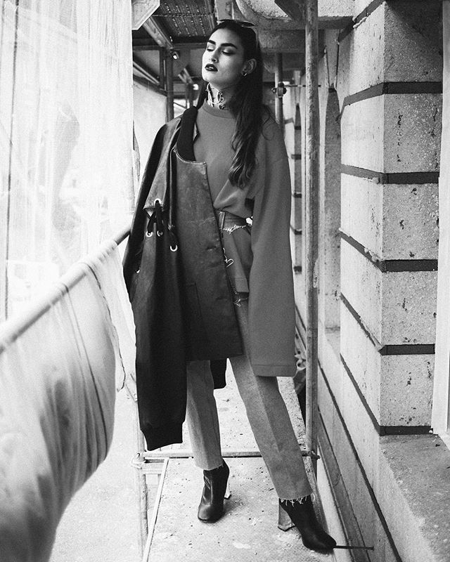 A stylish woman poses in an urban setting wearing trendy clothes for a fashion editorial.