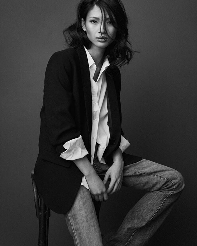 A sophisticated woman in a blazer poses in a striking black and white studio portrait. Perfect for fashion and branding.