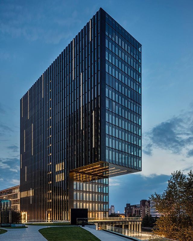 A modern skyscraper stands tall against a twilight sky, showcasing sleek architecture and urban design.