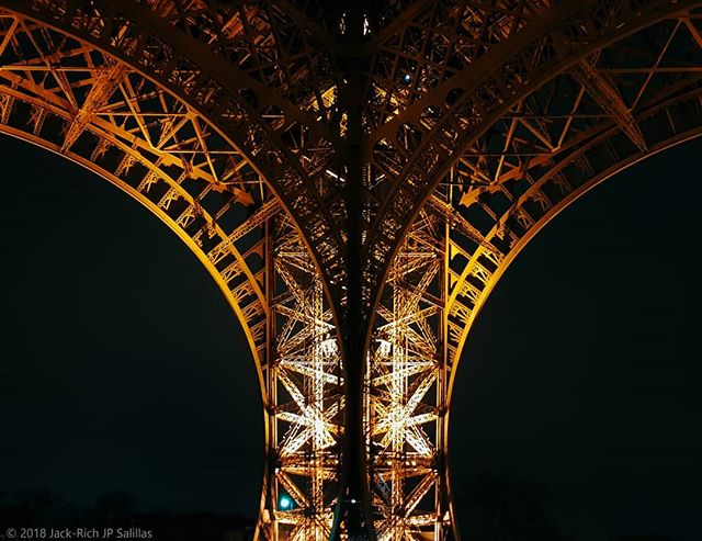 Illuminated Eiffel Tower architectural details at night, a symbol of Paris and a popular travel destination.