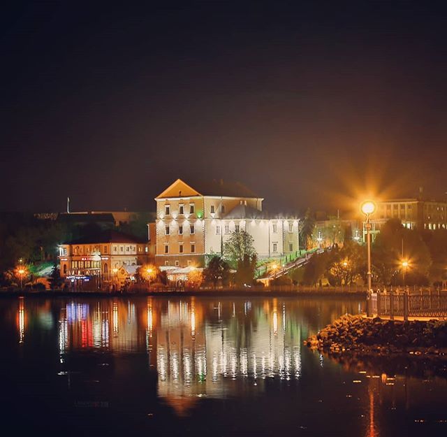 Night view of a castle reflected in a lake, creating a serene and picturesque cityscape.