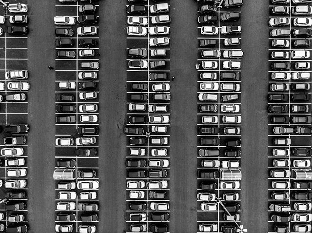 Aerial view of a parking lot filled with neatly arranged cars, creating a sense of order and urban organization.