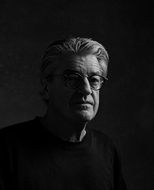 A black and white portrait of a mature man wearing glasses, exuding a serious and professional demeanor.