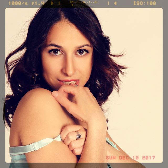A brunette woman with a ring poses in a vintage style, creating a sensual and intimate atmosphere.