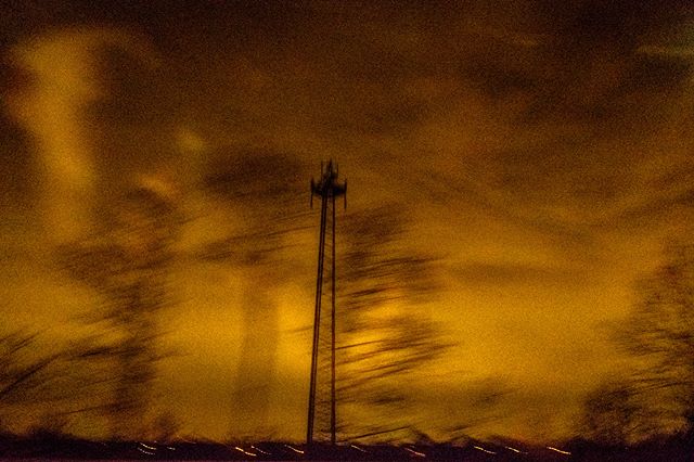 A blurred, long exposure shot of a cell tower at night with a warm color palette. 