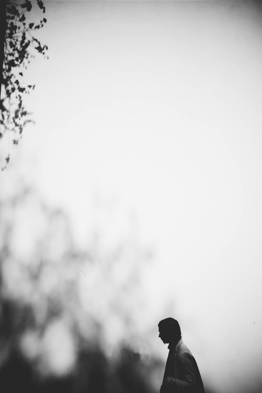 Silhouette of a man walking, creating a moody, contemplative atmosphere. Black and white, minimalist style.