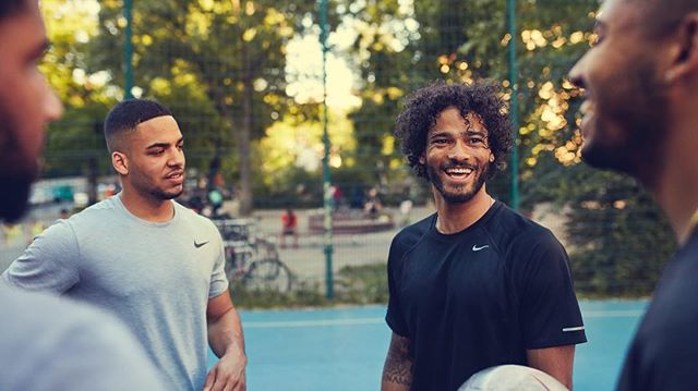 A group of men in athletic wear are smiling and socializing on an outdoor court. 