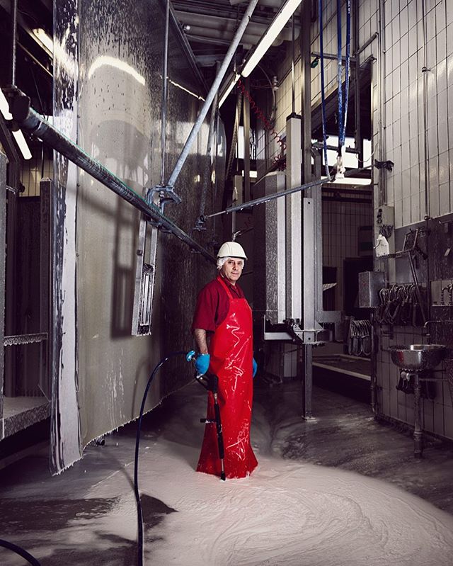 A factory worker in safety gear stands amid machinery on a production line.