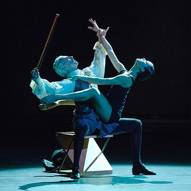 A man and a woman perform an intense dance routine on a stage in a dark setting.