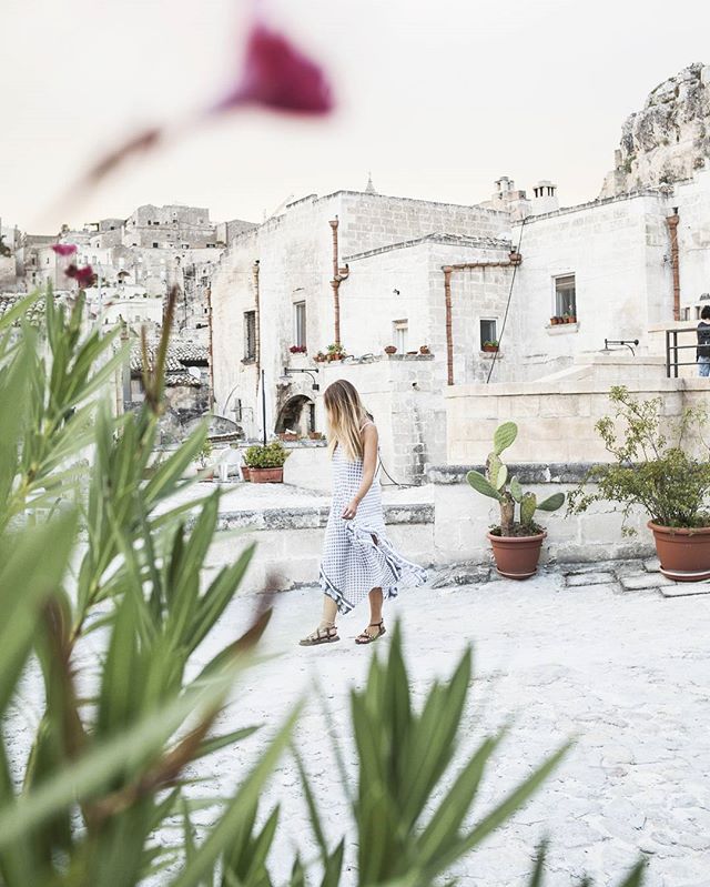 A woman in a dress walks in a historic city, capturing a serene travel moment.