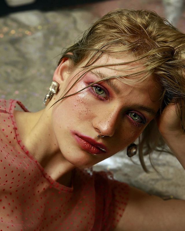 A woman with pink eyeshadow and red lipstick poses for a beauty shot.