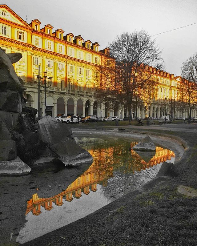 An elegant building's reflection shimmers in a fountain, creating a tranquil urban scene.