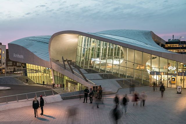 Modern train station exterior at dusk with blurred motion of people passing by in the city.