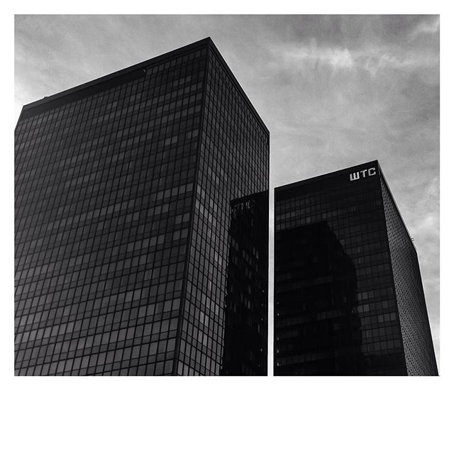 A striking black and white photo of modern buildings against a cloudy sky.