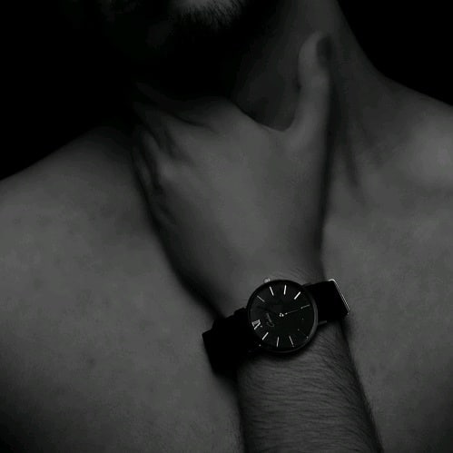 Close-up of a man's wrist with a stylish watch, showcasing a minimalist aesthetic in black and white.