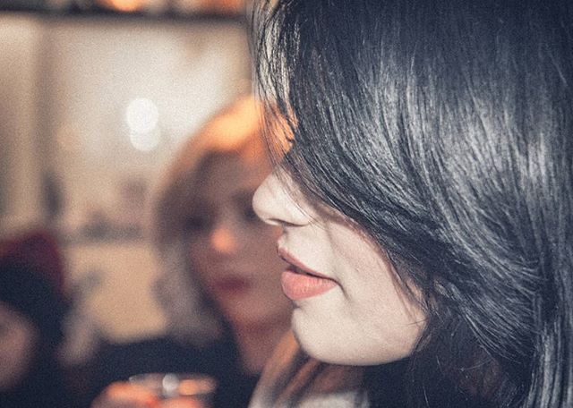 A close-up of a woman with dark hair and a blurred background suggests an intimate moment at an event.