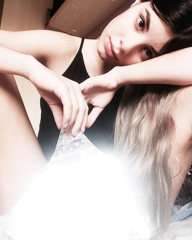 A young woman with dark hair poses intimately, creating a dreamy and natural atmosphere.