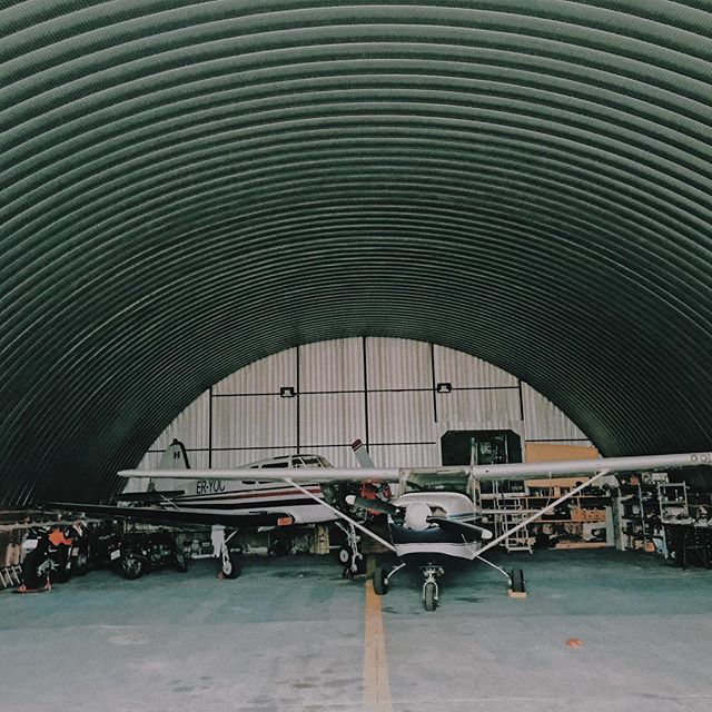 Planes are parked inside a metal hangar, ready for maintenance and flight, providing secure storage for the aircraft.