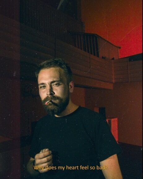 Contemplative man smoking, looking directly at the camera with a poignant expression.