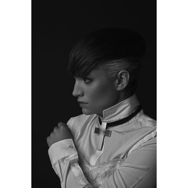 A monochrome portrait of a stylish woman with a unique hairstyle and collar.