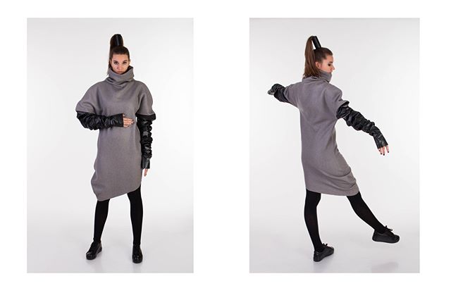 A woman models a gray dress with black sleeves and tights in a studio setting.