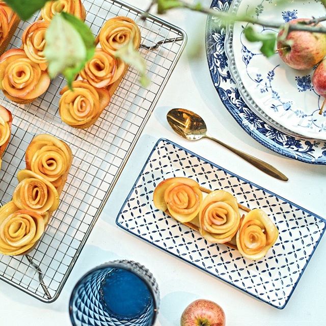 Artfully arranged apple rose pastries create a visually appealing dessert presentation on a clean, bright table.