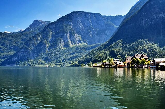 Scenic view of Hallstatt lake and village in Austria surrounded by majestic mountains under a clear blue sky.