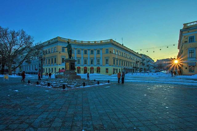 A statue in the city square with buildings in the background on a clear day.