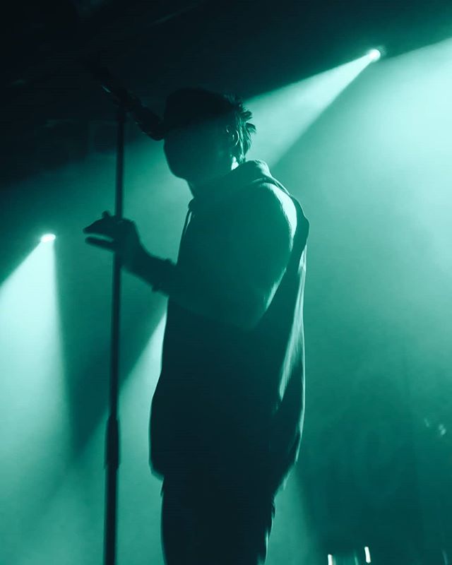 A silhouetted singer performs on stage with intense lighting, creating a dramatic atmosphere.