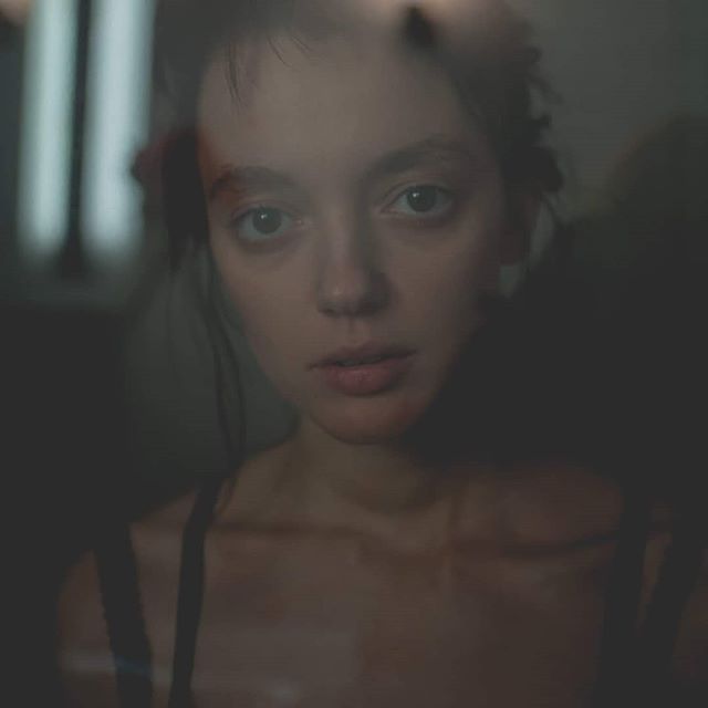 An intimate portrait of a woman looking through a window, with soft light and a contemplative mood.