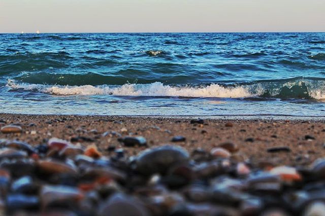 Calm blue ocean waves crash on a rocky beach, creating a tranquil and inviting scene.