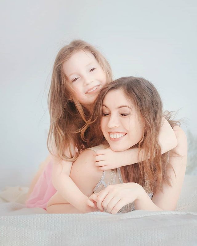 A loving mother and daughter share an intimate moment, embracing in a tender hug on a soft bed.