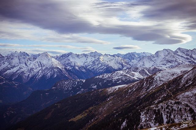 A scenic view of snow-capped mountains under a cloudy sky creates a tranquil nature landscape.