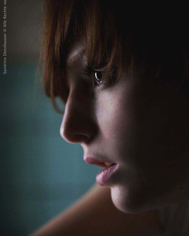 An introspective close-up captures a woman's gentle gaze in soft, natural light, creating a serene and emotional atmosphere.