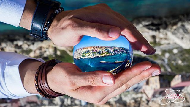A captivating cityscape is reflected in a crystal ball held in someone's hands, showcasing a unique travel perspective.